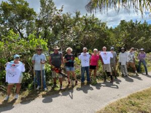 A diverse group of individuals standing on a path, with a sign in the background.